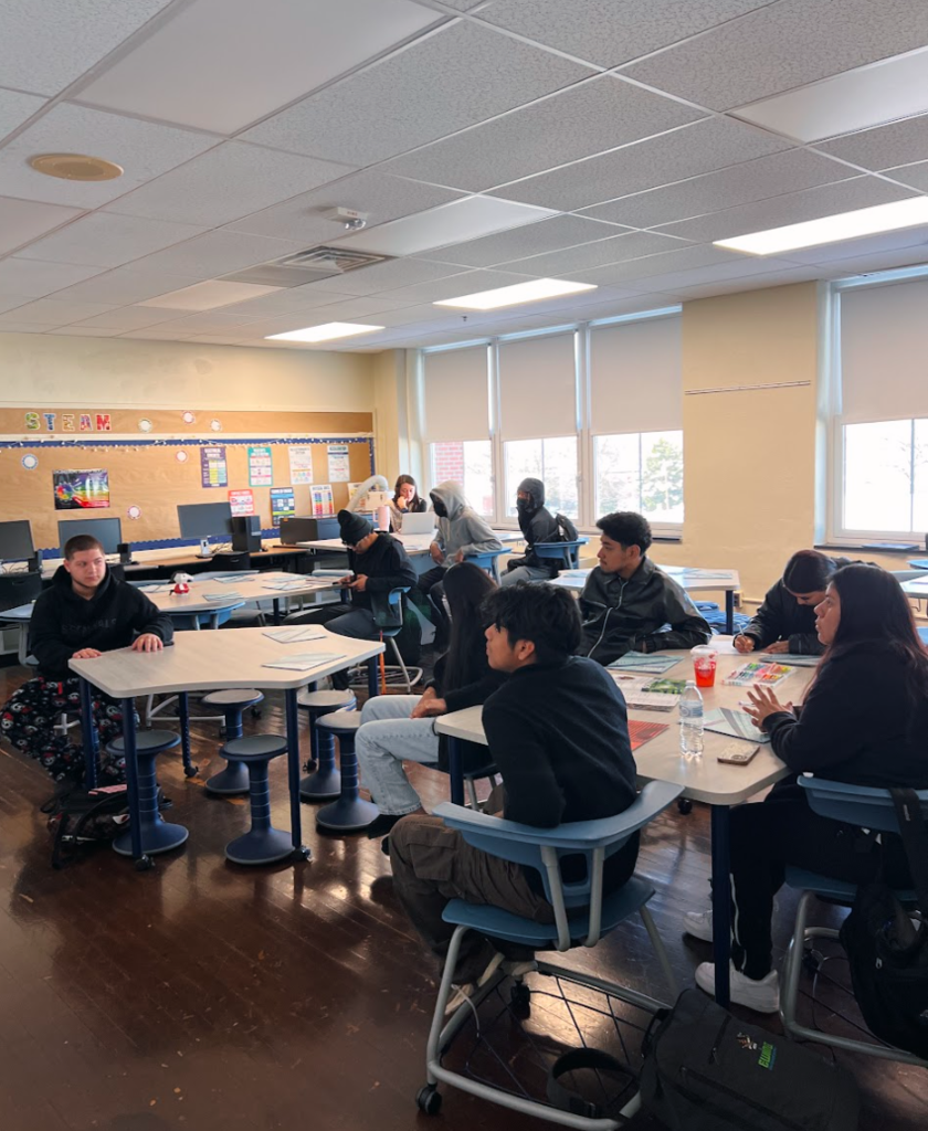 Students are in a classroom listening to a speaker give a presentation about going to the community college