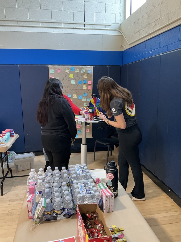 A student is spinning the wheel with a city year coach to win a prize