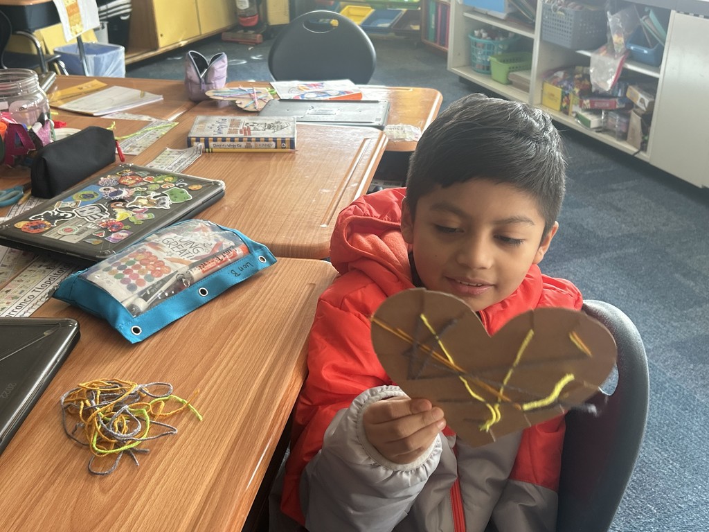 A student showing their yarn heart