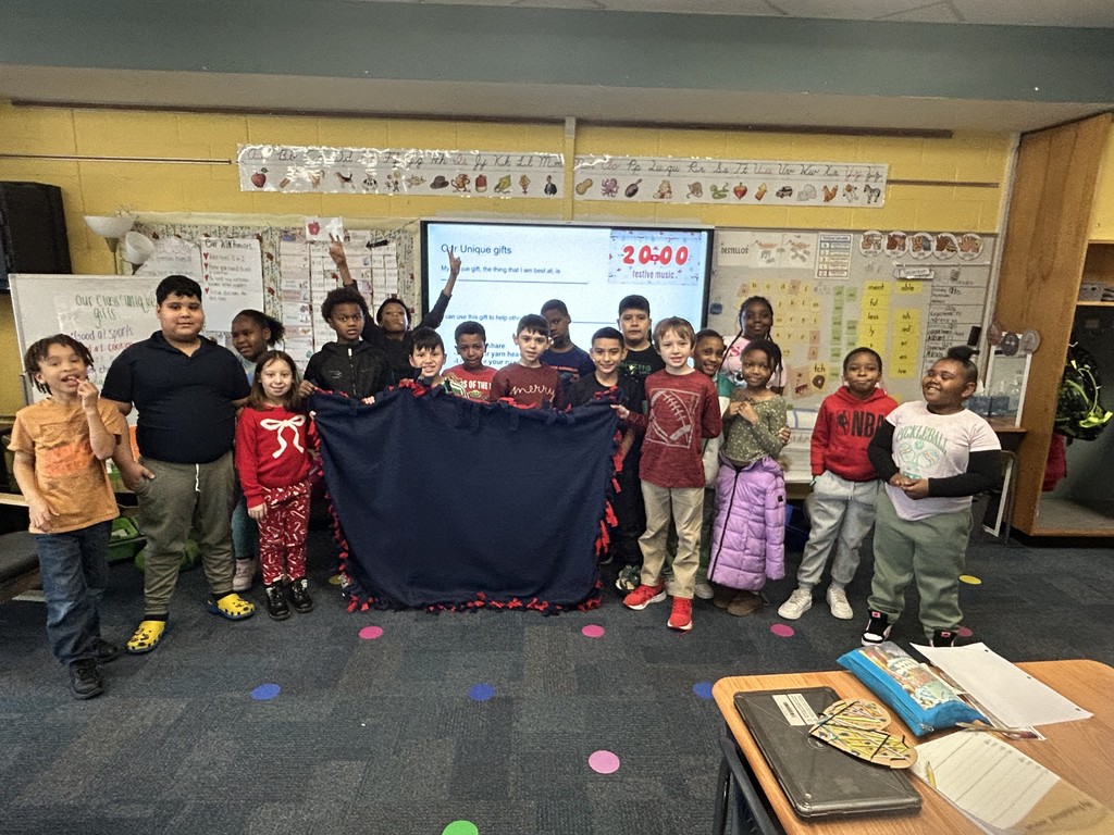 Students holding a blanket they made to donate to Ronald McDonald House Charities