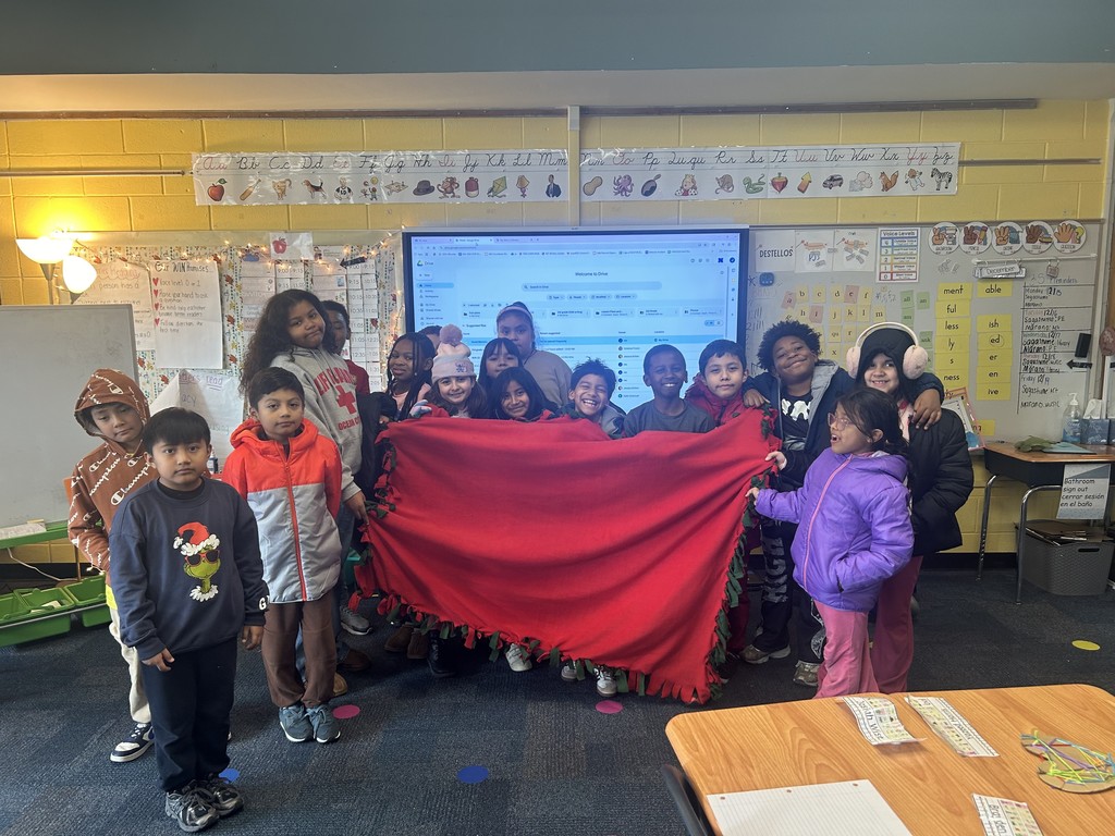 Students holding a blanket they made to donate to Ronald McDonald House Charities