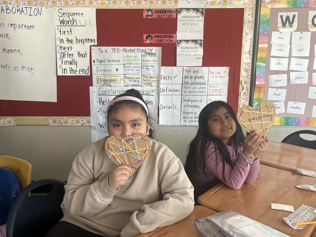 Two students showing their yarn hearts they made