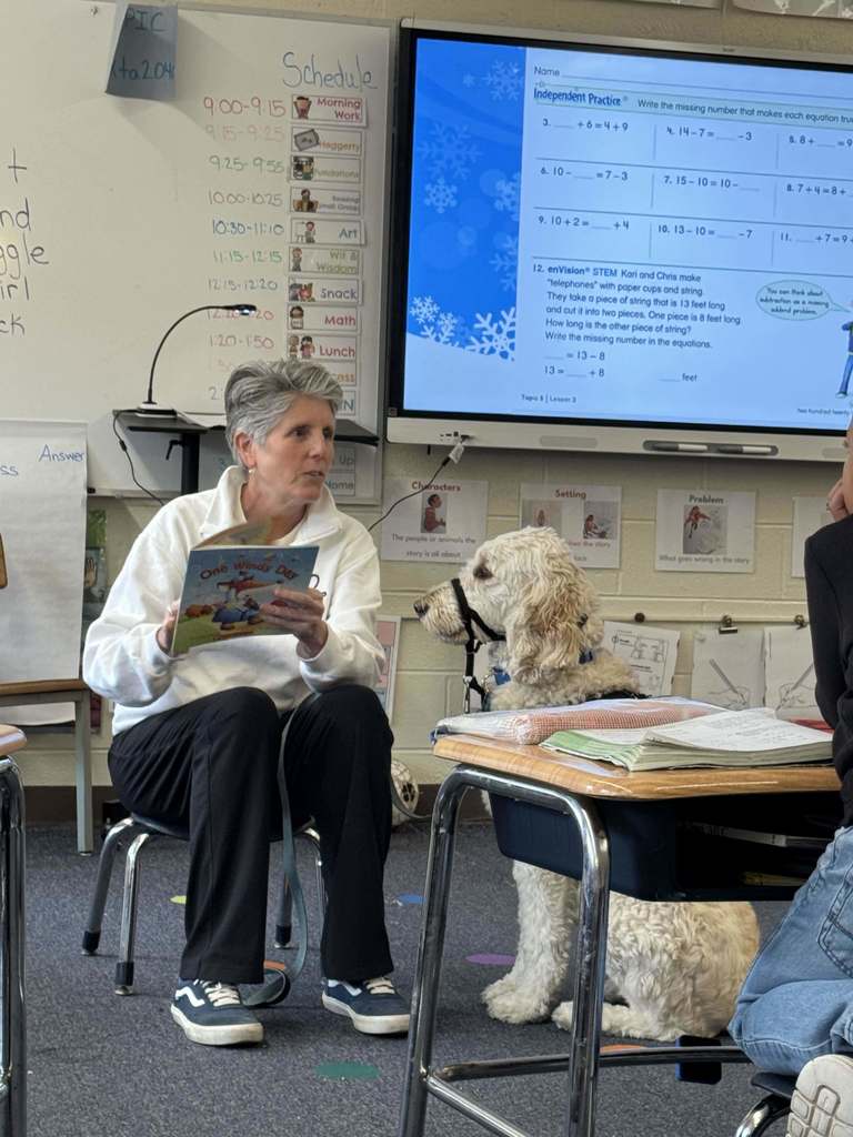 Nutmeg the service dog sits and listens while a story is read to first graders.