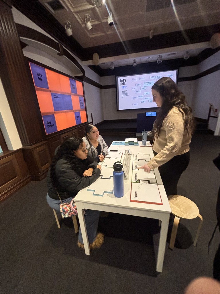 Two girls are talking with a museum worker at a table