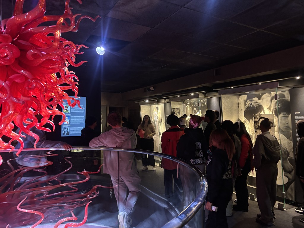A group of students are listening to a presenter from the museum