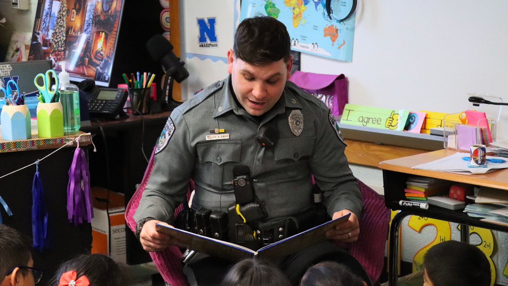 Officer Dinolfi reading a storybook to students at Whitehall. 