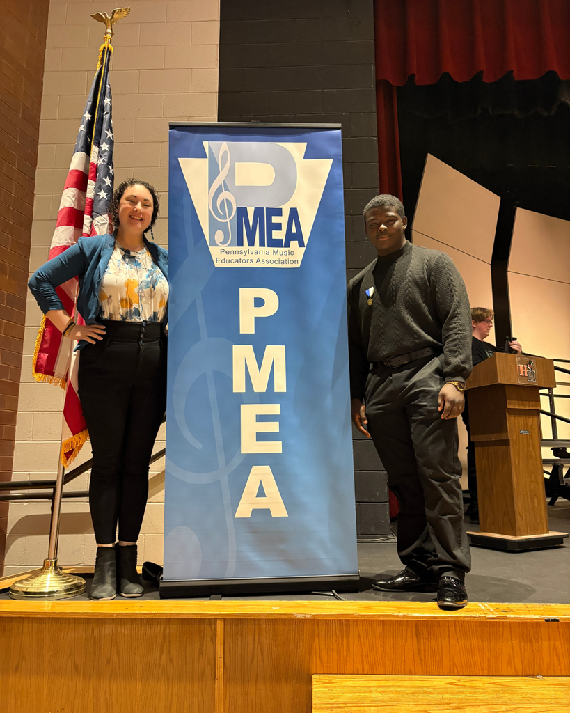 Eddie and Mrs. Danoff standing in next to a PMEA banner on stage.