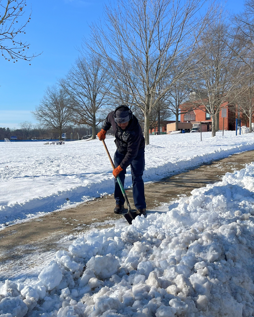 Operations staff member shoveling sidewalk to clear off the snow.