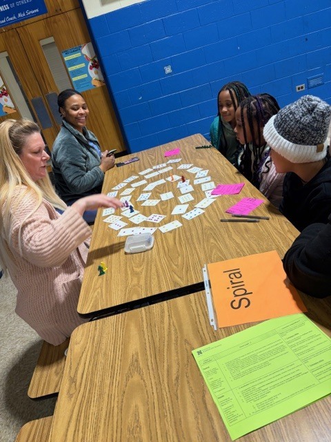 A teacher and a family playing Spiral at math night