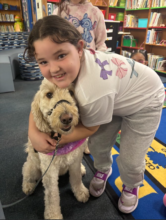 A student hugging Nutmeg the dog