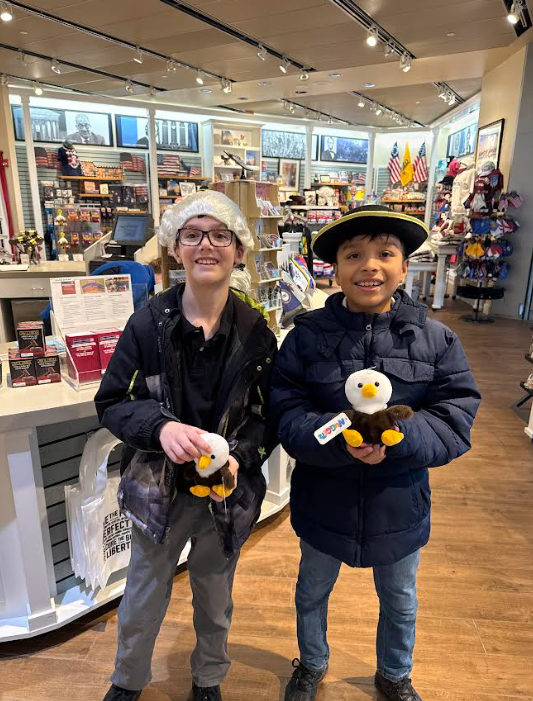 5th graders pose in the gift shop holding a stuffed eagle.