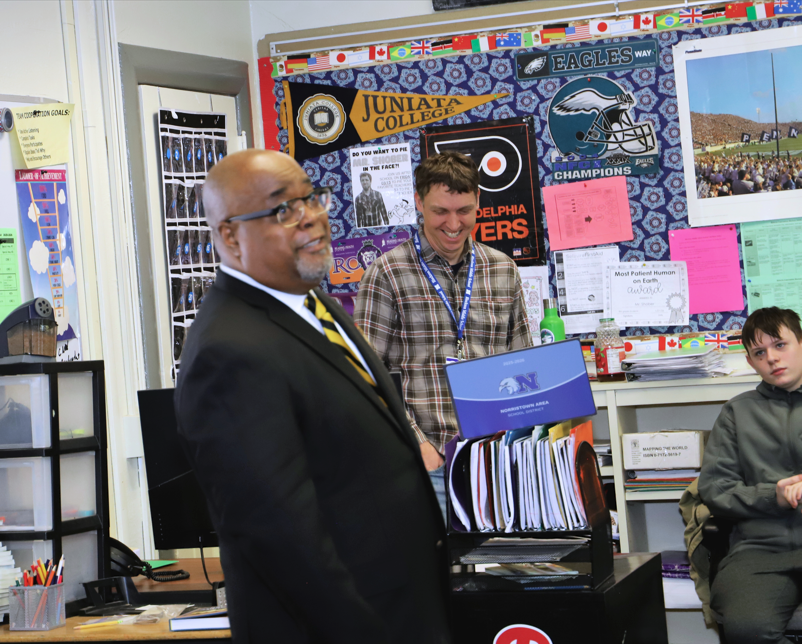 Alpha Phi Alpha members speak to students in a classroom.