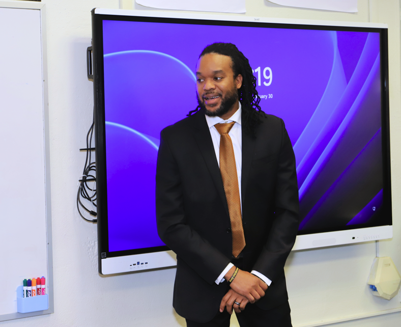 Alpha Phi Alpha members speak to students in a classroom.