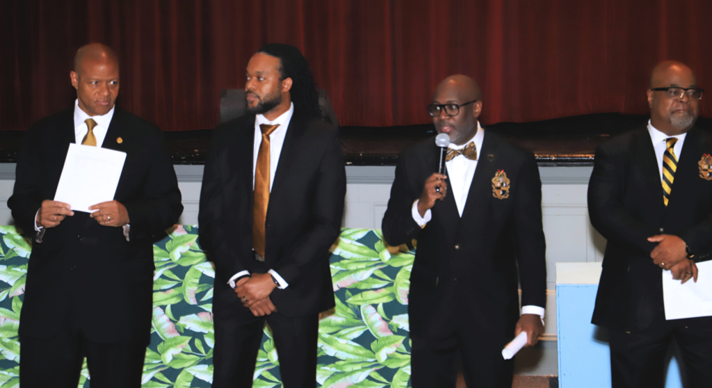 Alpha Phi Alpha members speak to students in the auditorium.