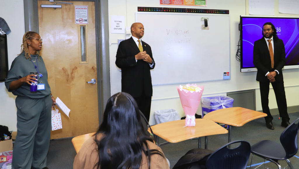 Alpha Phi Alpha members speak to students in a classroom.