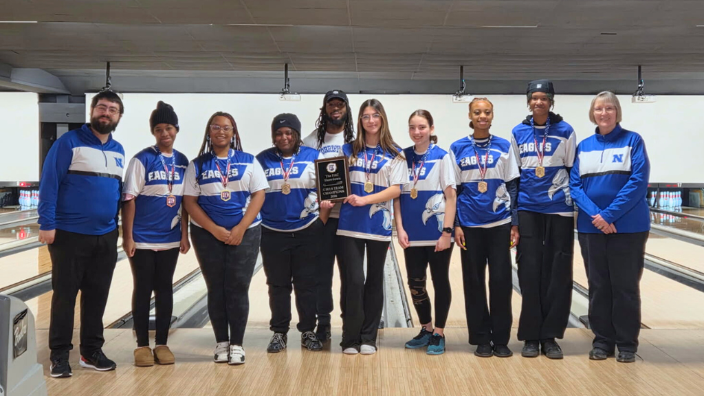 Girls Bowling Team and Coaches pose for photo in front of bowling lanes.
