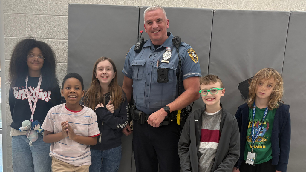School Resource Officer posing for photo with group of students.