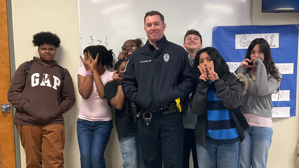 School Resource Officer posing for photo with group of students.