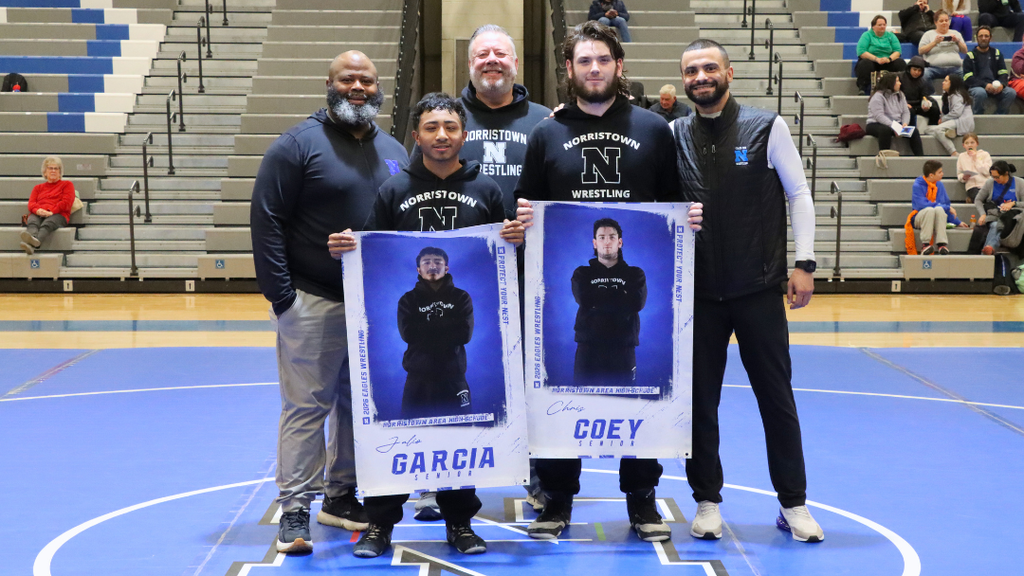 Wrestling seniors pose for photo with coaches.