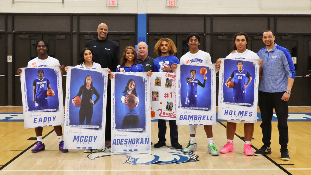 Boys Basketball senior players and managers standing with coaches holding their senior posters.
