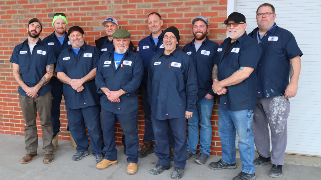 NASD maintenance team pose for a group photo in front of red brick wall. 