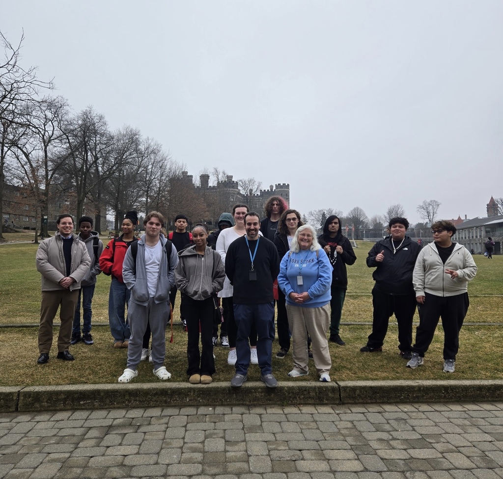 A group of students and teachers are outside posing together for a group shot.