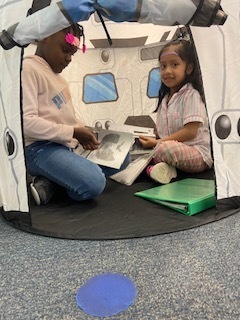 Two students reading inside of their spaceship tent