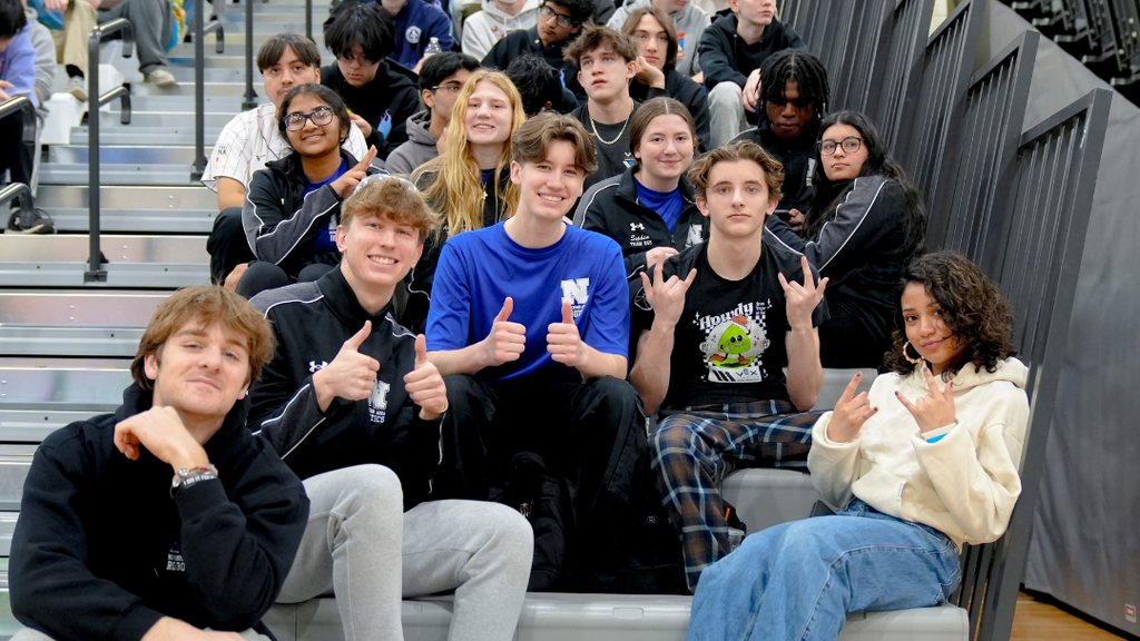 NAHS robotics team sitting on bleachers posing for a photo.