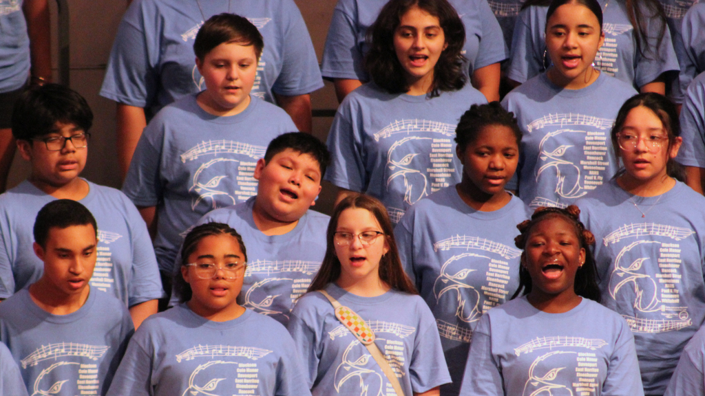 Close up of middle school choir studnets sining on stage. 