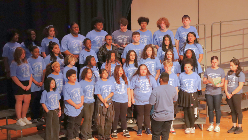 Group of middle school students singing on stage risers. 