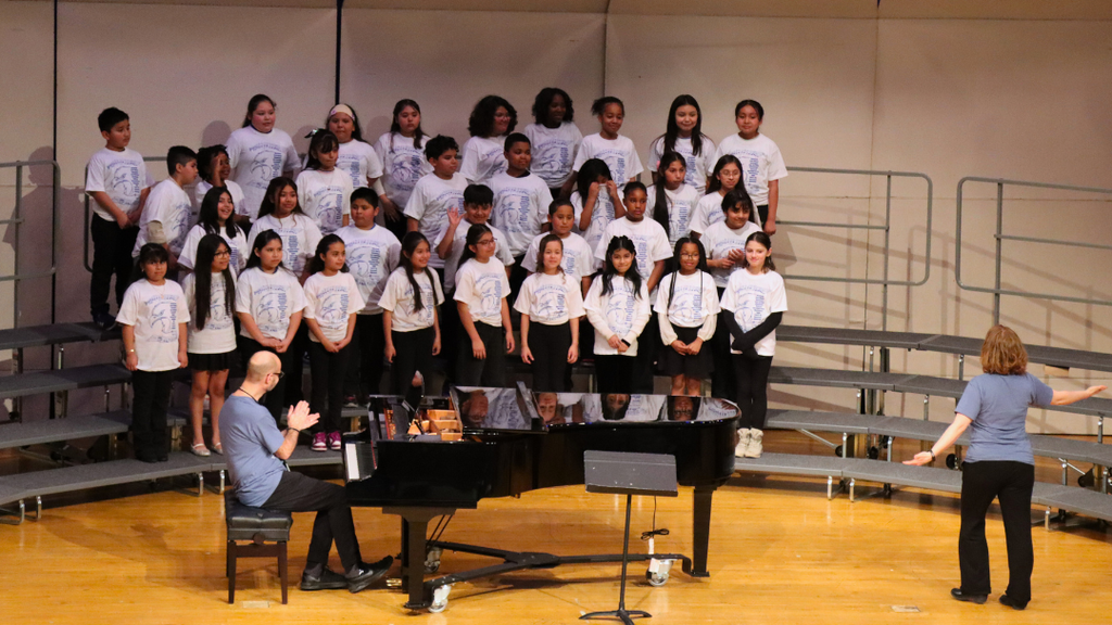 Group of elementary students performing on stage risers. 