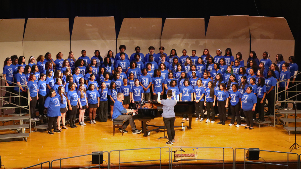 NAHS choir sining on stage risers with a conductor and pianist.