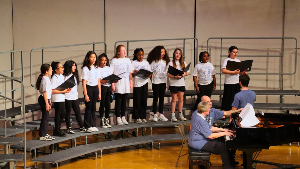 Small group of elementary students sining on stage risers. 