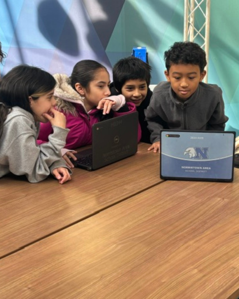 Group of 4 studnets working on their Dream It, Design It project with their Chromebooks.