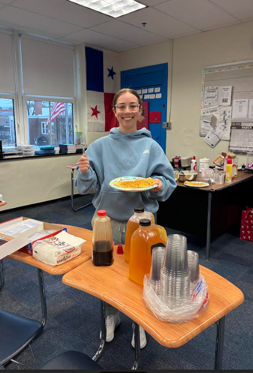 A teacher is posing with her waffle and juice