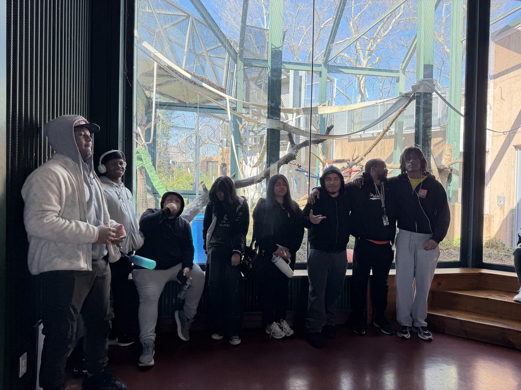 A group of students are posing in the primate exhibit
