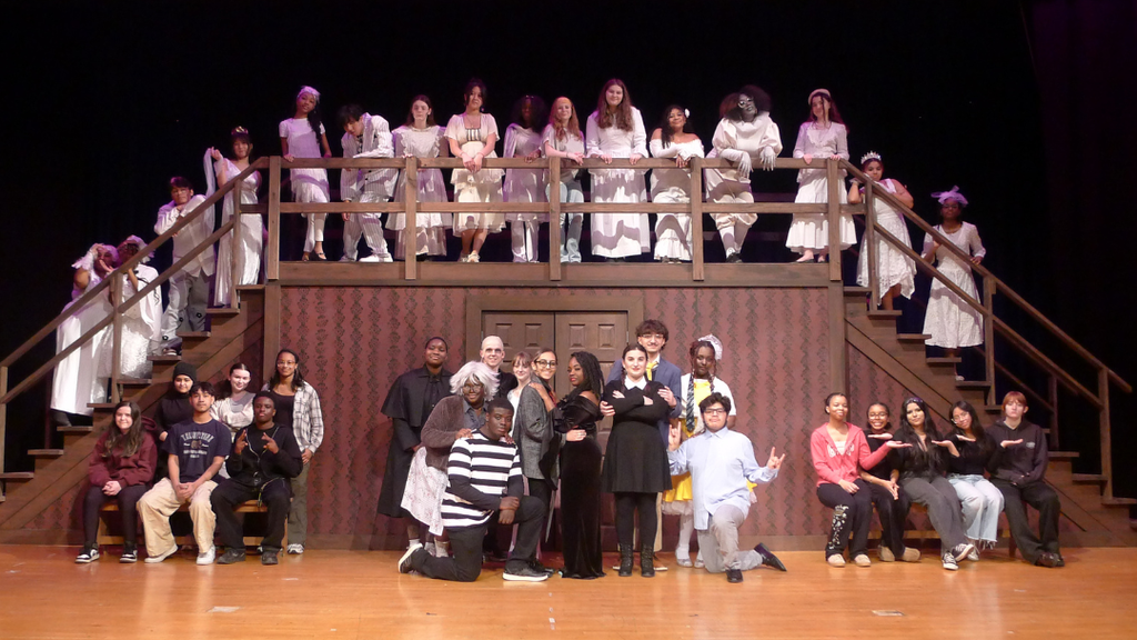 High school students pose for photo for their spring musical on stage.