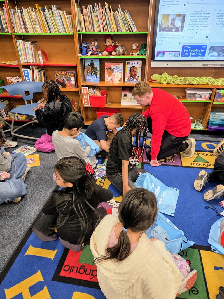 Students working with a volunteer to add name plates to their books
