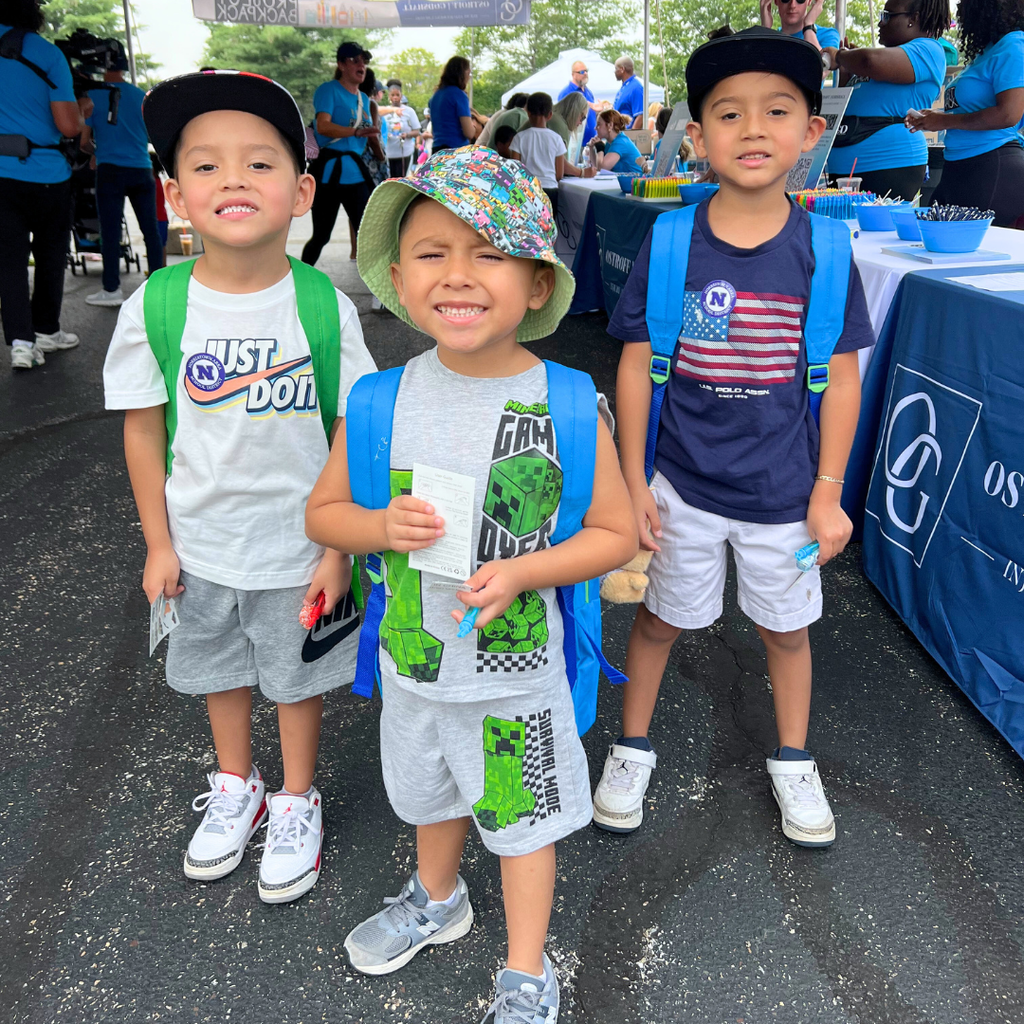 Three studnets smiling with their new backpacks.