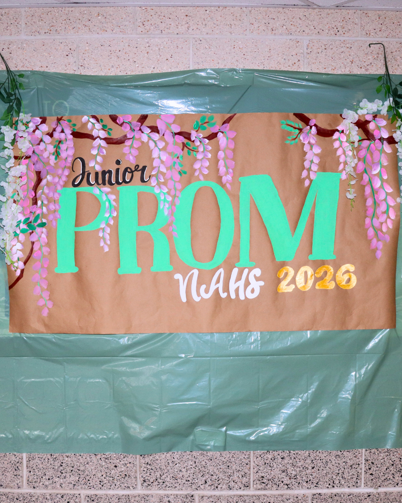 Brown paper banner with text "Junior Prom NAHS 2026" and flowers painted onto it.