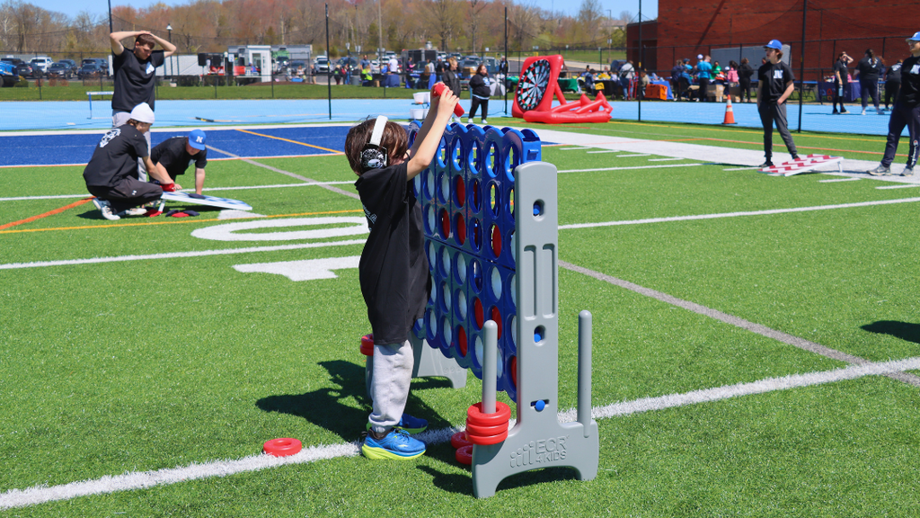 Young student playing yard game of connect four. 