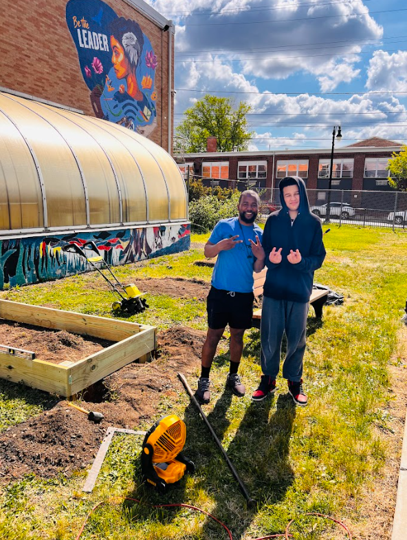 A student and a teacher are posing outside of the