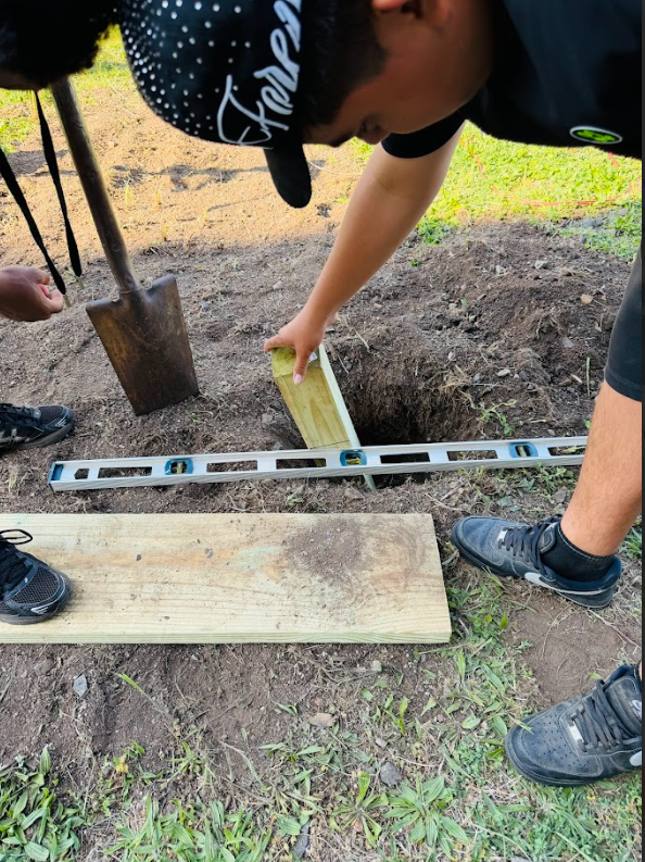 A student is measuring a plank of wood for the garden