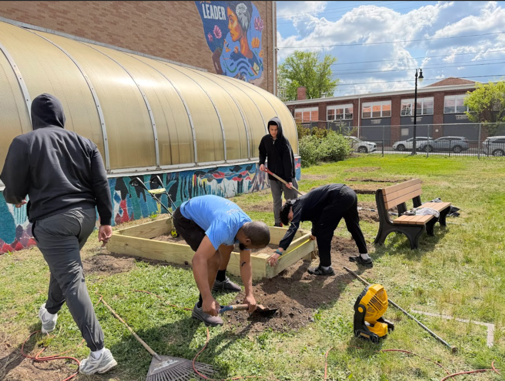 two students and one staff are working on the garden outside