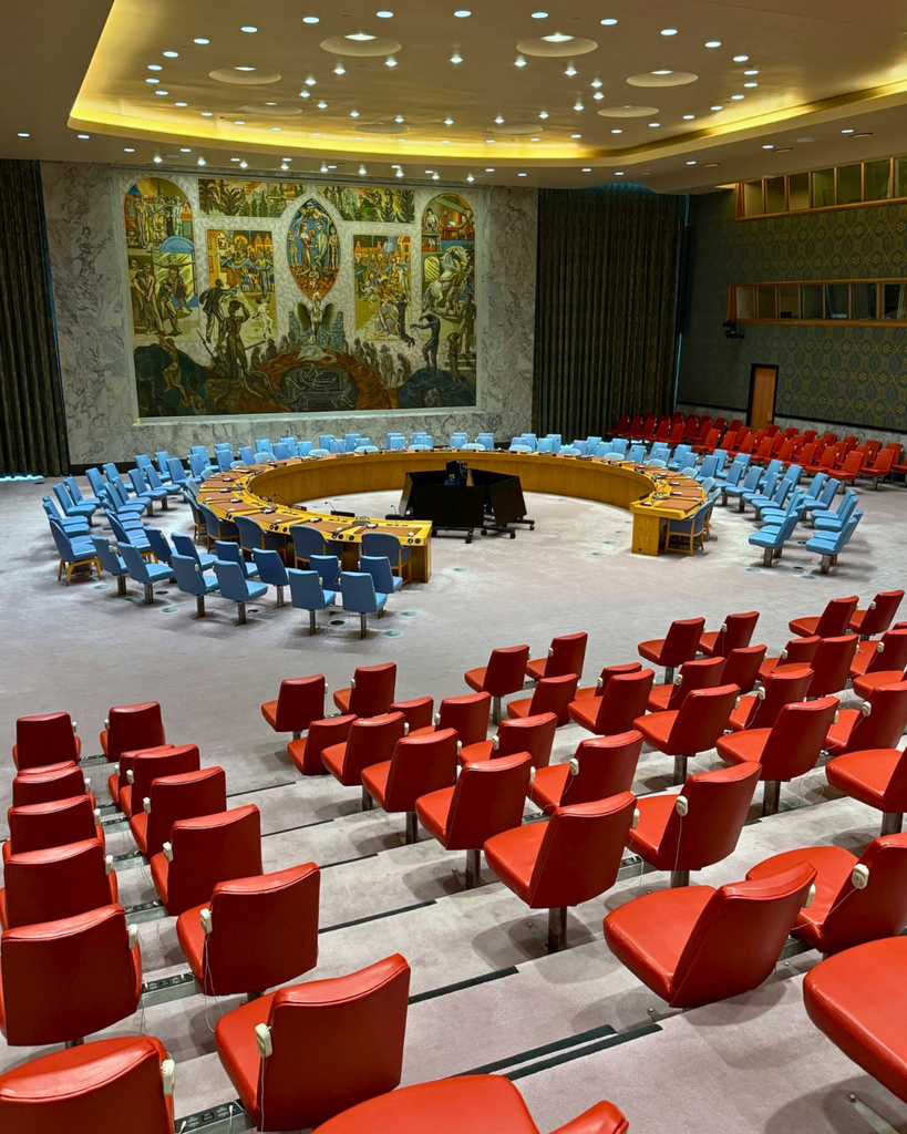 Room in the United Nations with empty chairs and mosaic wall. 