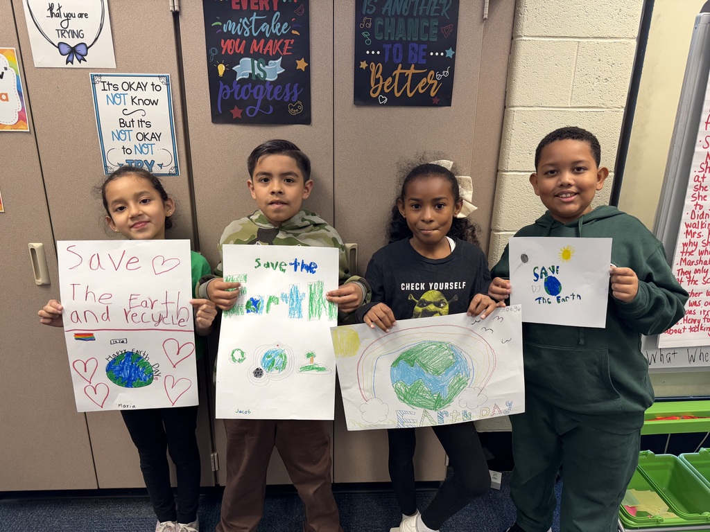 Second graders show their Earth Day posters.
