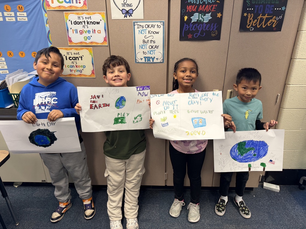 Second graders show their Earth Day posters.