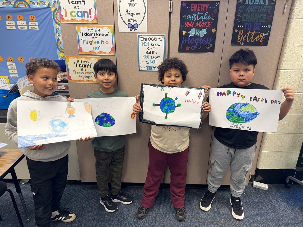 Second graders show their Earth Day posters.