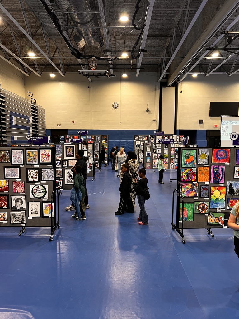 Students and families are looking at art pieces hanging on display