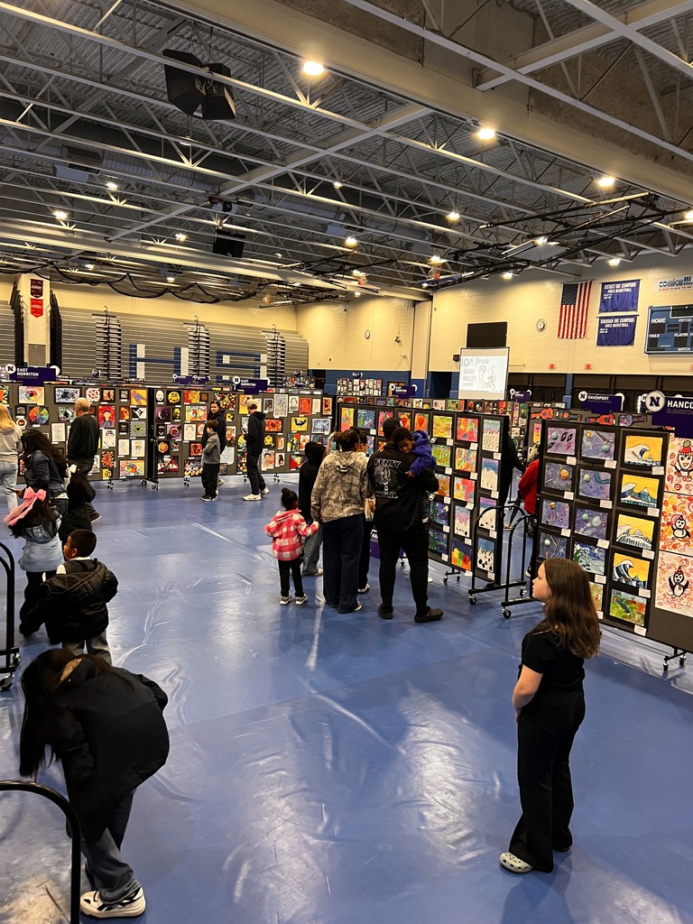 Students and families are looking at art pieces hanging on display